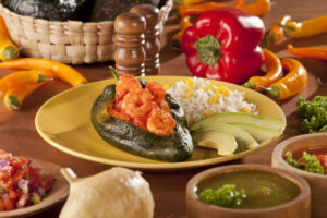 "Chile relleno or Poblano pepper stuffed with shrimps in tomato sauce, served with rice and avocado slices."