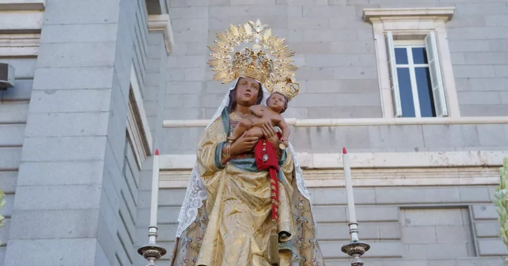 Imagen de la Virgen de la Almudena con dos candelabros a los lados