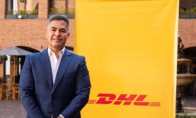 Representante de DHL Express delante de cartel de la compañía