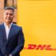 Representante de DHL Express delante de cartel de la compañía