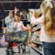 Familia en supermercado, niña tomando foto a pareja con carro