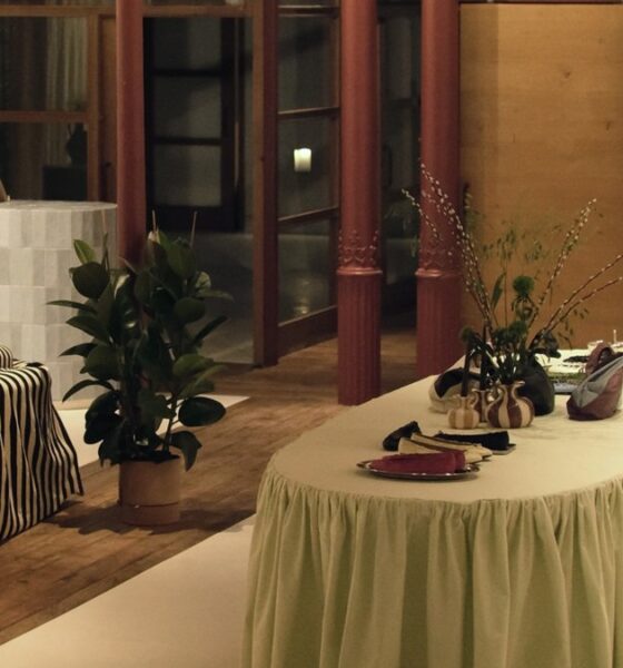 Maniquí con vestido de rayas, junto a sofá , planta y mesa con floreros, Al fondo entrada a la tienda